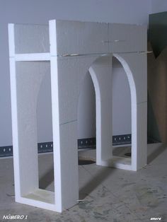 two white arches sitting next to each other on the floor in front of a wall