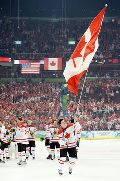 the canadian flag is being carried by hockey players