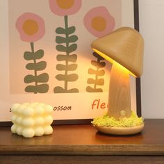 a mushroom lamp sitting on top of a wooden table next to a lit up flower