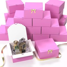 several pink boxes with gold bows are stacked on top of each other in front of a white background