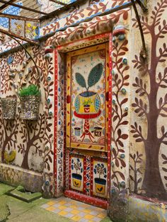 an artisticly decorated building with potted plants on the outside and paintings on the walls