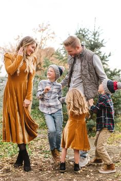 a family walking together in the woods during their fall photo session with one child holding his mom's hand