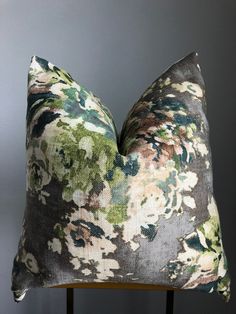 a pillow on a chair with a gray wall behind it and a green floral pattern