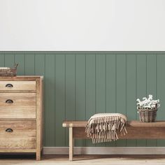 a wooden bench sitting in front of a green wall