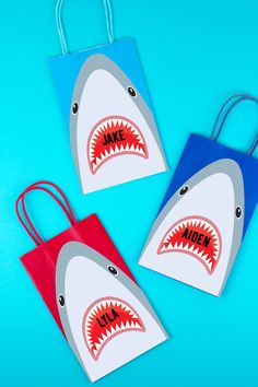 three paper bags with shark's teeth on them, one is red and the other blue