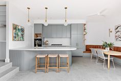 a kitchen with gray cabinets and wooden stools next to an island counter top in the middle