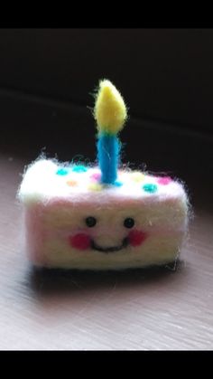 a piece of cake with a smiley face on it and a candle sticking out of the top