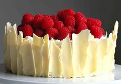 a cake with white frosting and raspberries on top