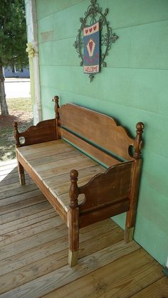 a wooden bed sitting on top of a wooden floor next to a green wall with a clock above it