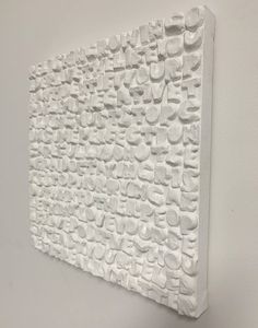 a white wall hanging on the side of a building with lots of small holes in it