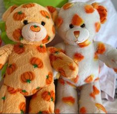 two teddy bears sitting next to each other with pumpkins painted on their faces and arms