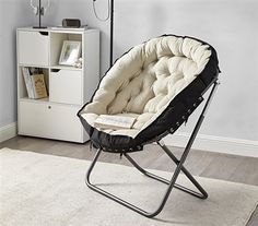 a black and white chair in a living room with a book shelf on the far wall