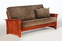 a wooden futon couch with two pillows on it's back and armrests