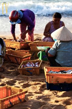 two women are sitting on the beach with baskets