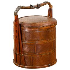 an antique bamboo basket with handles and leather straps on the handle, sitting in front of a white background