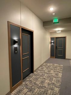 an empty hallway with two black doors and carpet