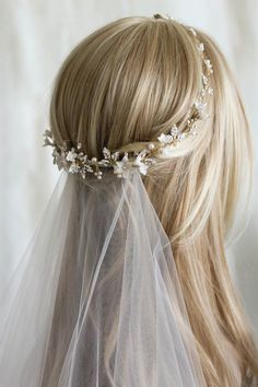 a blonde woman wearing a veil with flowers on the top and hair comb in her left hand