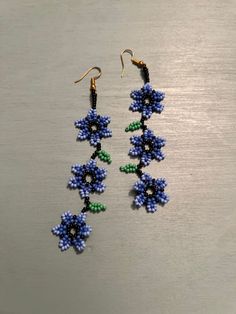 two pairs of beaded earrings with flowers on them sitting on top of a table