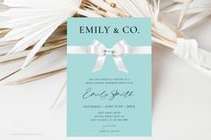 a blue and white wedding card with a bow on the front is surrounded by palm leaves