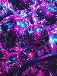 many shiny disco balls are stacked together in purple and blue colors, with the lights on them