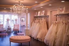 a room filled with lots of wedding dresses hanging on the wall and a chandelier