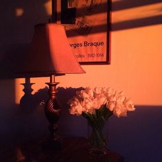 a vase with flowers on a table next to a lamp