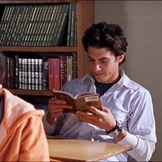 two people sitting at a table reading books