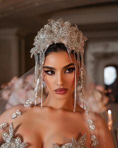 a woman in a wedding dress wearing a veil and tiara with flowers on it