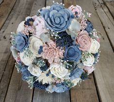 a bridal bouquet with blue and pink flowers on a wooden table in front of wood planks