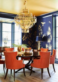 a dining room table with orange chairs and a chandelier