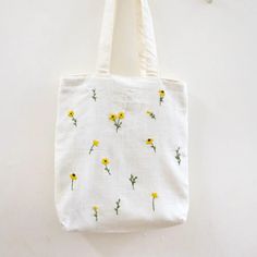 a white tote bag with yellow flowers on it