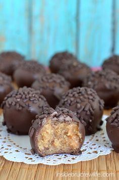 three chocolate covered desserts sitting on top of a white doily next to a wooden table