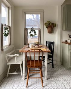 a kitchen table with two chairs and a potted plant on the window sill