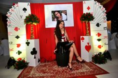 a woman sitting on top of a suitcase in front of a red wall with playing cards