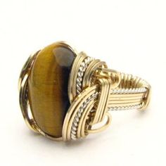 "Handmade Wire Wrap Two Tone Sterling Silver/14kt Gold Filled Tiger Eye Agate Ring  Sizing and shipping is ALWAYS FREE with a 14 day \"No Questions Asked\" return policy. Gemstone sizes available: XS (16x12mm 5/8x1/2 inch) S (18x13mm 3/4x1/2 inch 10+ct) M (25x18mm 1x3/4 inch 20+ct) L (30x22mm 11/8 x7/8 inch 25+ct) This ring is made with real gems. I made it myself, so if you see a setting you like and want a different gem in it, I can put in another one as they are not finished. I can probably do it for the same price or real close. I can make these either in gold or sterling silver; just email me for a price. If any of the wires look loose in the picture it is because I do not finish them until I size them. They will not be loose when you get them.  We can also offer matching earrings, pe Artisan Oval Hand-wrapped Jewelry, Elegant Brown Rings With Natural Stones, Artisan Hand Wrapped Oval Jewelry, Handmade Oval Gold Gemstones, Yellow Gold Agate Ring, Brown Polished Agate Jewelry, Unique Brown Jewelry For Anniversary, Gold Cabochon Agate Jewelry, Gold Agate Cabochon Jewelry