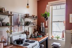 a kitchen with an oven, stove and shelves filled with pots and pans on the wall