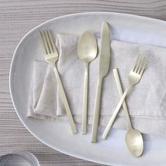 a white plate topped with silverware on top of a wooden table next to utensils