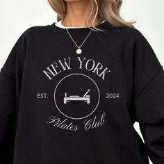 The New York Pilates club sweatshirt is a cozy yet stylish garment designed for both comfort and a chic athleisure look. Typically crafted from soft, high-quality fabric, it features a relaxed fit that allows for easy movement during workouts or lounging. Available in various colors, this sweatshirt embodies a modern aesthetic, making it a perfect addition to any fitness enthusiast's wardrobe, whether you're in the studio or on the streets. Please reach out with any questions! Gildan 18000 Sweat Long Sleeve Logo Print Sweatshirt For Loungewear, Logo Print Crew Neck Sweater For Loungewear, Crew Neck Sweater With Logo For Loungewear, Long Sleeve Sweater With Logo For Loungewear, Cotton Workout Sweatshirt With Logo Print, Casual Logo Print Sweatshirt For The Gym, Casual Sweatshirt With Logo Print For Gym, Crew Neck Logo Print Sweater For Loungewear, Fleece Tops With Logo Print For Loungewear