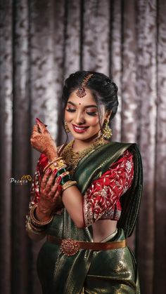 a woman in a green and red sari holding her hands up to her chest