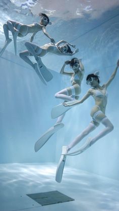 three women in white swimsuits are floating under water