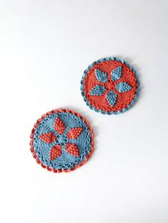 two crocheted coasters sitting next to each other on a white table top