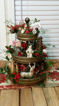 a three tiered christmas tree with ornaments and decorations on the top, sitting on a wooden floor