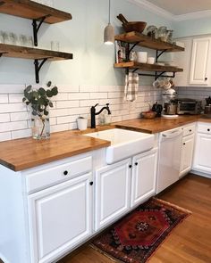 a kitchen with white cabinets and wooden counter tops, along with open shelving above the sink