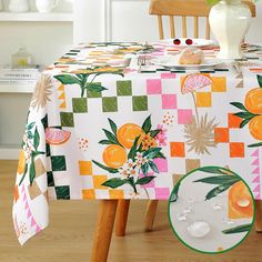 the table cloth is decorated with oranges and other colorful things on it's surface