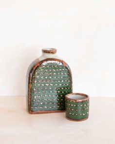 two green vases sitting next to each other on a white tableclothed surface