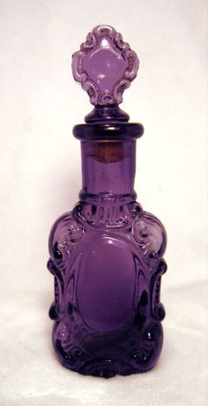 a purple glass bottle sitting on top of a white table