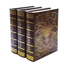 three brown books with gold designs on the covers, one is closed to reveal an intricate design