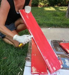 a woman in white gloves is working on a red piece of wood that has been painted