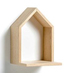 a wooden shelf with a small house on it's side, against a white wall