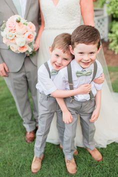 two young boys are hugging each other in front of the bride and groom